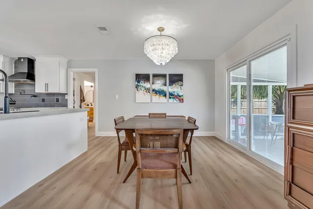a kitchen with stainless steel appliances kitchen island granite countertop a table chairs and a refrigerator