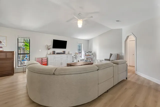 a living room with furniture and a dining table with wooden floor