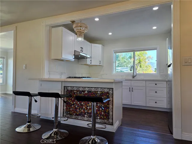 a kitchen with stainless steel appliances granite countertop a stove a sink dishwasher and a fireplace with wooden floor