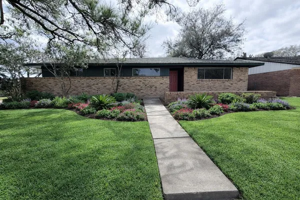 a front view of a house with a yard and potted plants