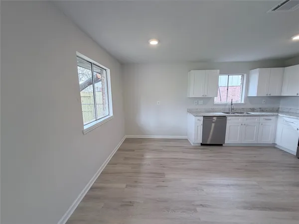 a view of kitchen with granite countertop white cabinets and sink