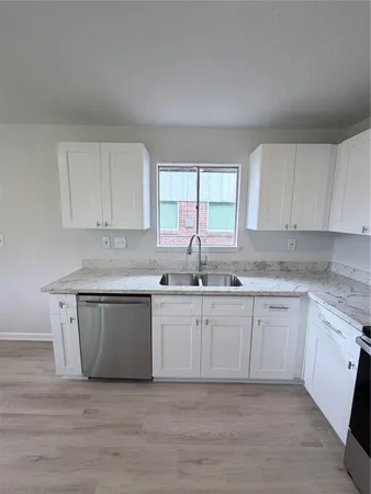 a kitchen with granite countertop white cabinets and a sink