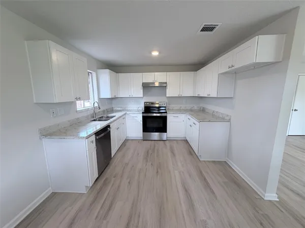 a kitchen with granite countertop a stove top oven and cabinets