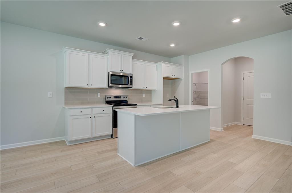 119 St Anne's Place Covington, GA 30016 - Photo 9 of 30 a kitchen with white cabinets and stainless steel appliances