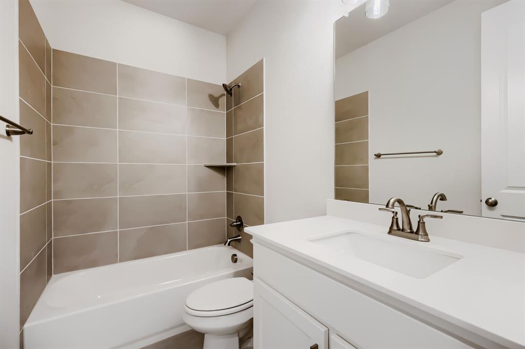 4407 Windy Point Road Oak Point, TX 75068 - Photo 18 of 27 Full bathroom featuring a white vanity with an integrated sink, a large wall-mounted mirror, and a bathtub with tile surround extending to the ceiling