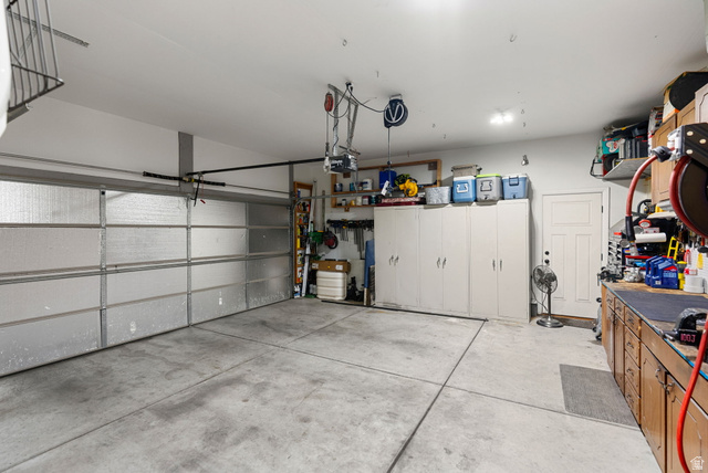 2485 South 1100th Street West Logan, UT 84321 - Photo 25 of 53 Spacious garage featuring a sectional garage door, concrete flooring, extensive built-in cabinetry, and a work bench with upper shelving