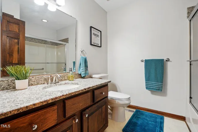 a bathroom with a granite countertop sink a toilet and mirror