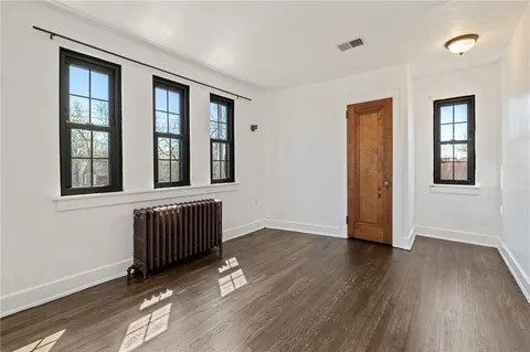 a view of an empty room with glass door and wooden floor