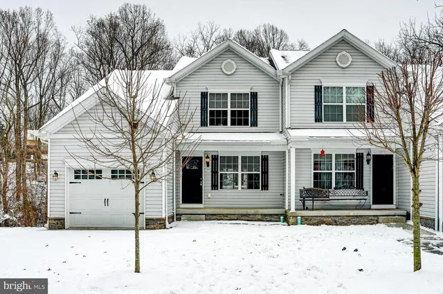 a front view of a house with a yard covered in snow