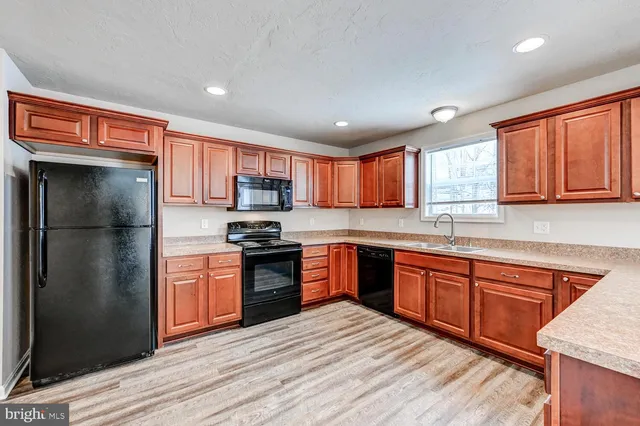a large kitchen with stainless steel appliances granite countertop a refrigerator stove top oven and large window