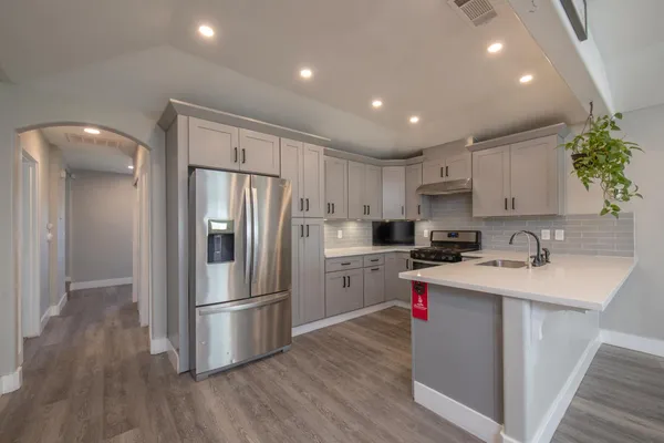 a kitchen with a sink stainless steel appliances and wooden floor