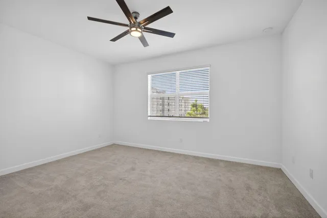 an empty room with a window and a fan