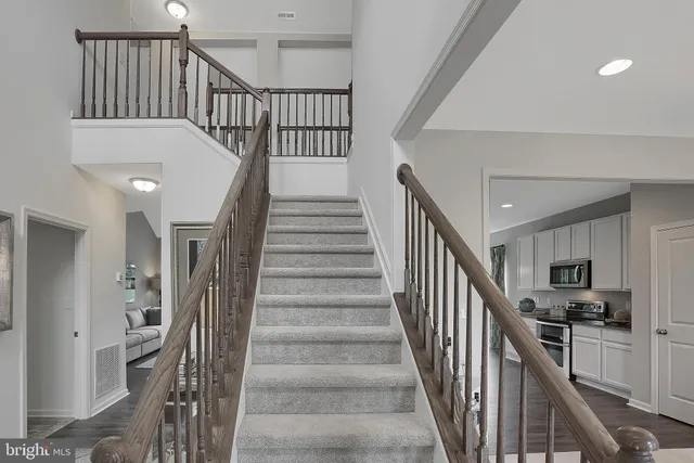 a view of staircase and kitchen with wooden floor and pendant lights