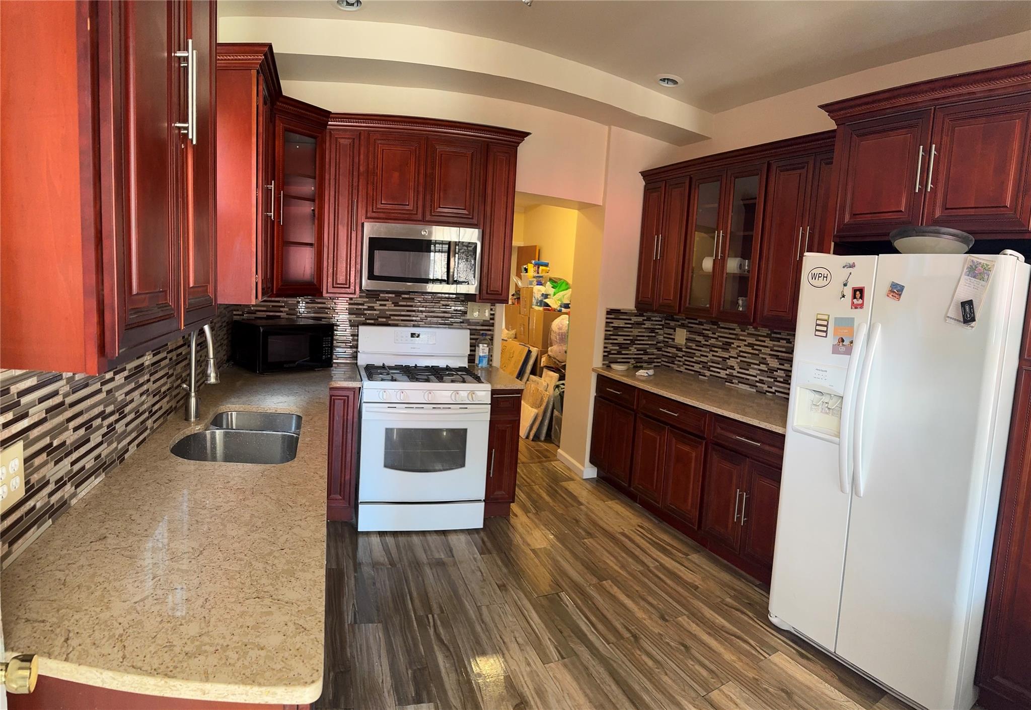 776 Hewitt Place Bronx, NY 10455 - Photo 12 of 20 a kitchen with wooden cabinets and white appliances