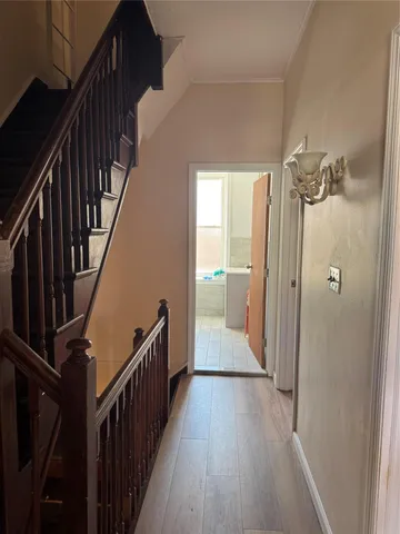 a view of a hallway with wooden floor and staircase