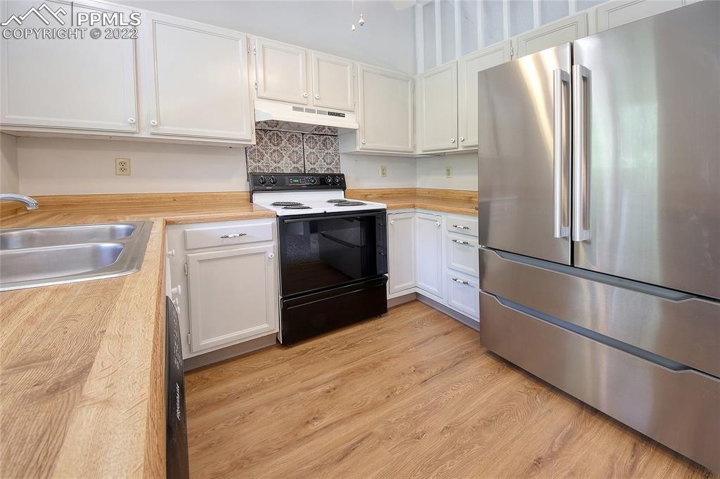 541 Blossom Field Road Fountain, CO 80817 - Photo 7 of 30 a kitchen with a refrigerator stove and white cabinets