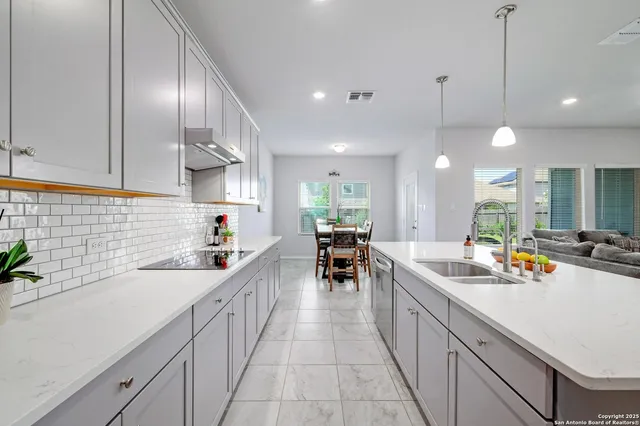 a kitchen with stainless steel appliances a sink a stove and chairs