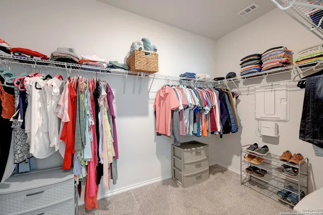 a view of walk in closet with clothes and shoes