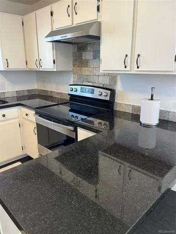 a kitchen with granite countertop a stove and cabinets