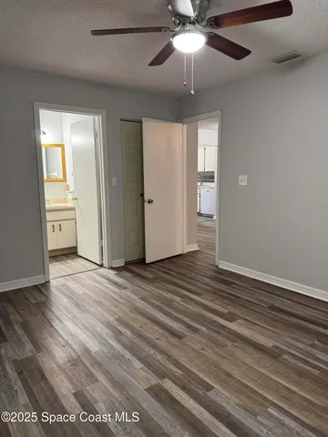 an empty room with wooden floor and ceiling fan