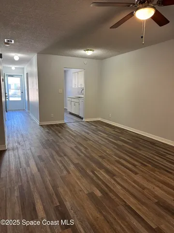 an empty room with wooden floor fan and windows