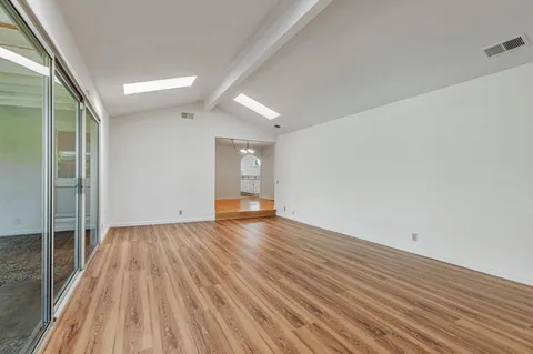 an empty room with wooden floor fan and windows