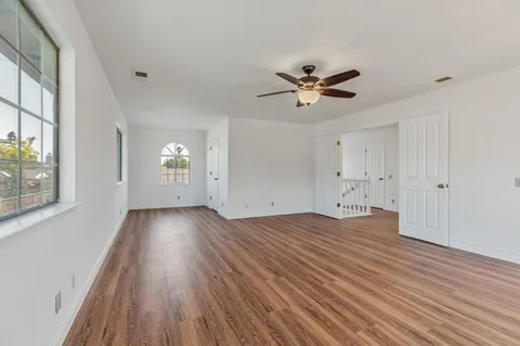 a view of an empty room with a window and wooden floor