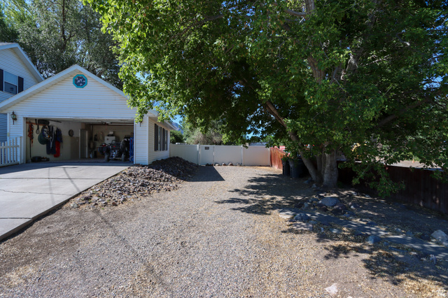270 East 100 North Monroe, UT 84754 - Photo 33 of 65 Two-car garage with white vinyl siding, a concrete driveway, and an adjacent gravel parking area