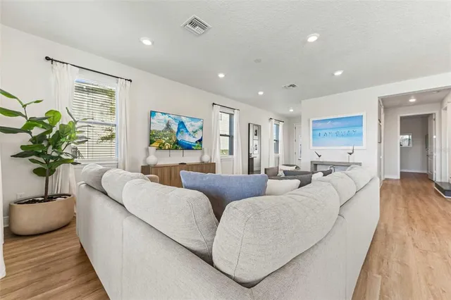 a living room with furniture kitchen view and a large window
