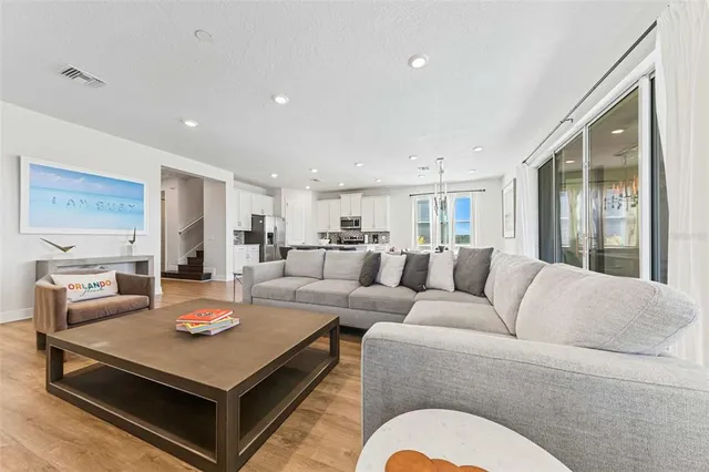 a kitchen with stainless steel appliances granite countertop a stove a refrigerator a sink and white cabinets with wooden floor