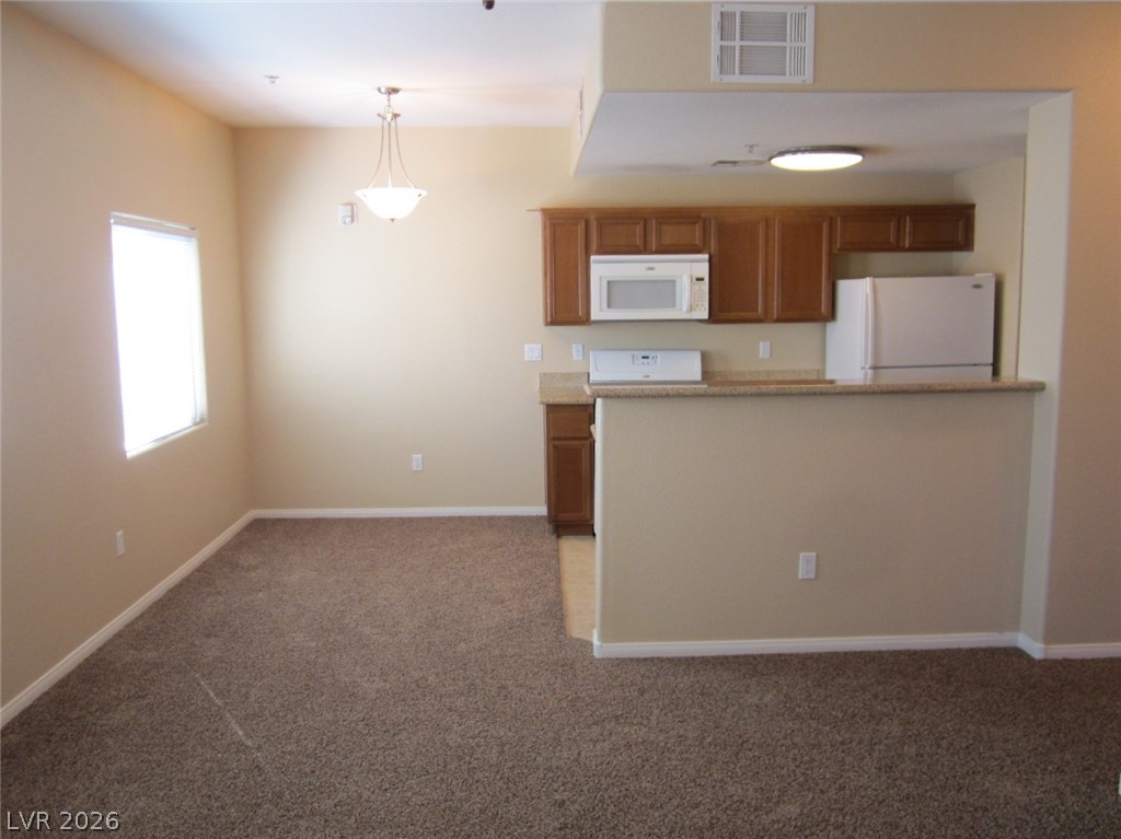 7701 West Robindale Road, Unit 262 Las Vegas, NV 89113 - Photo 9 of 26 A compact kitchen with functional appliances flows seamlessly into a cozy carpeted dining area.