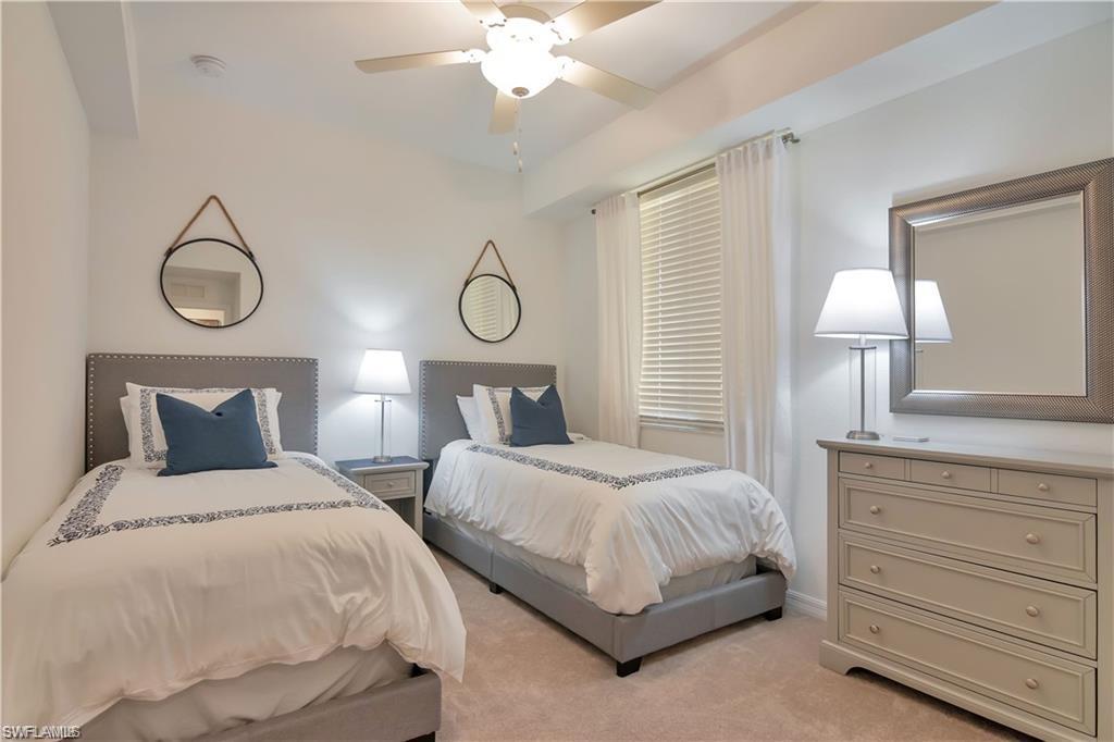 9590 Trevi Court, Unit 5337 Naples, FL 34113 - Photo 21 of 35 a bedroom with two beds and a chandelier