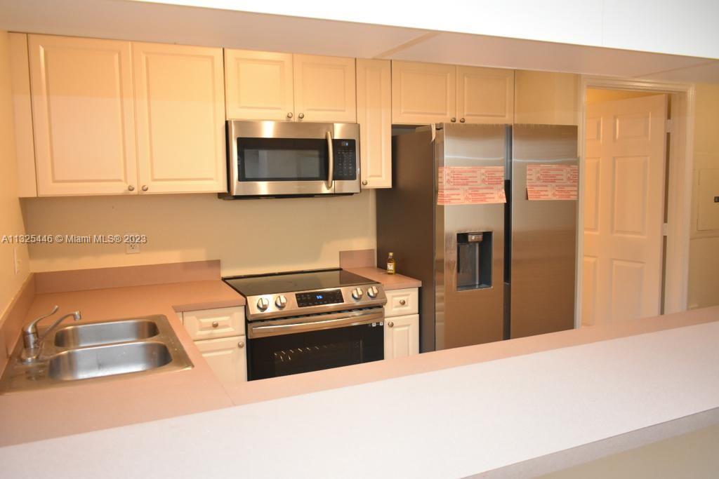 6520 West Sample Road, Unit 6520 Coral Springs, FL 33067 - Photo 12 of 33 a kitchen with stainless steel appliances a refrigerator a stove a microwave and cabinets