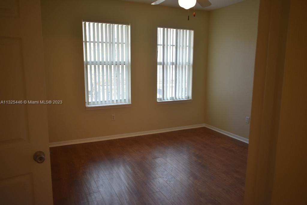 6520 West Sample Road, Unit 6520 Coral Springs, FL 33067 - Photo 20 of 33 an empty room with wooden floor and windows
