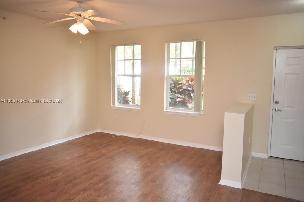 6520 West Sample Road, Unit 6520 Coral Springs, FL 33067 - Photo 5 of 33 an empty room with wooden floor fan and windows