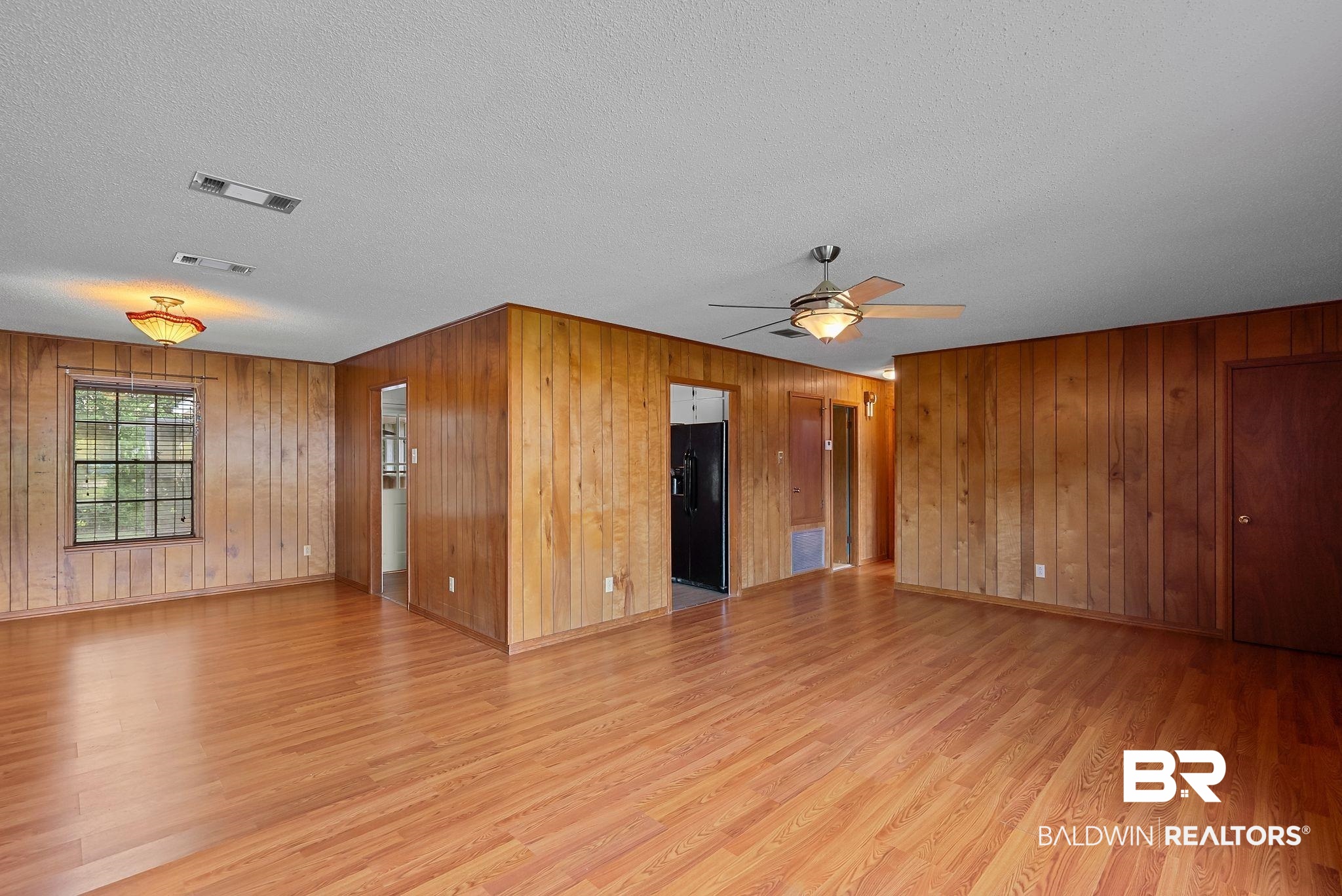 716 North Cedar Street Foley, AL 36535 - Photo 7 of 25 Expansive room featuring wood-finish flooring, wood paneling, a ceiling fan with integrated lighting, and multiple windows