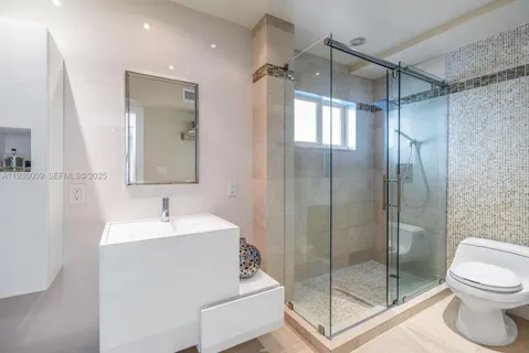a bathroom with a shower sink mirror and toilet