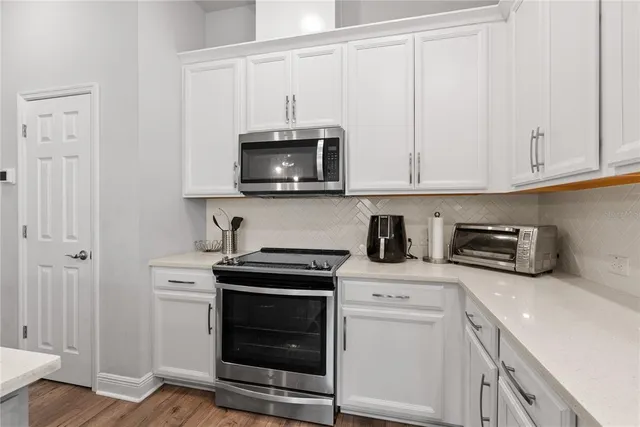 a kitchen with stainless steel appliances granite countertop grey cabinets a stove a sink and dishwasher