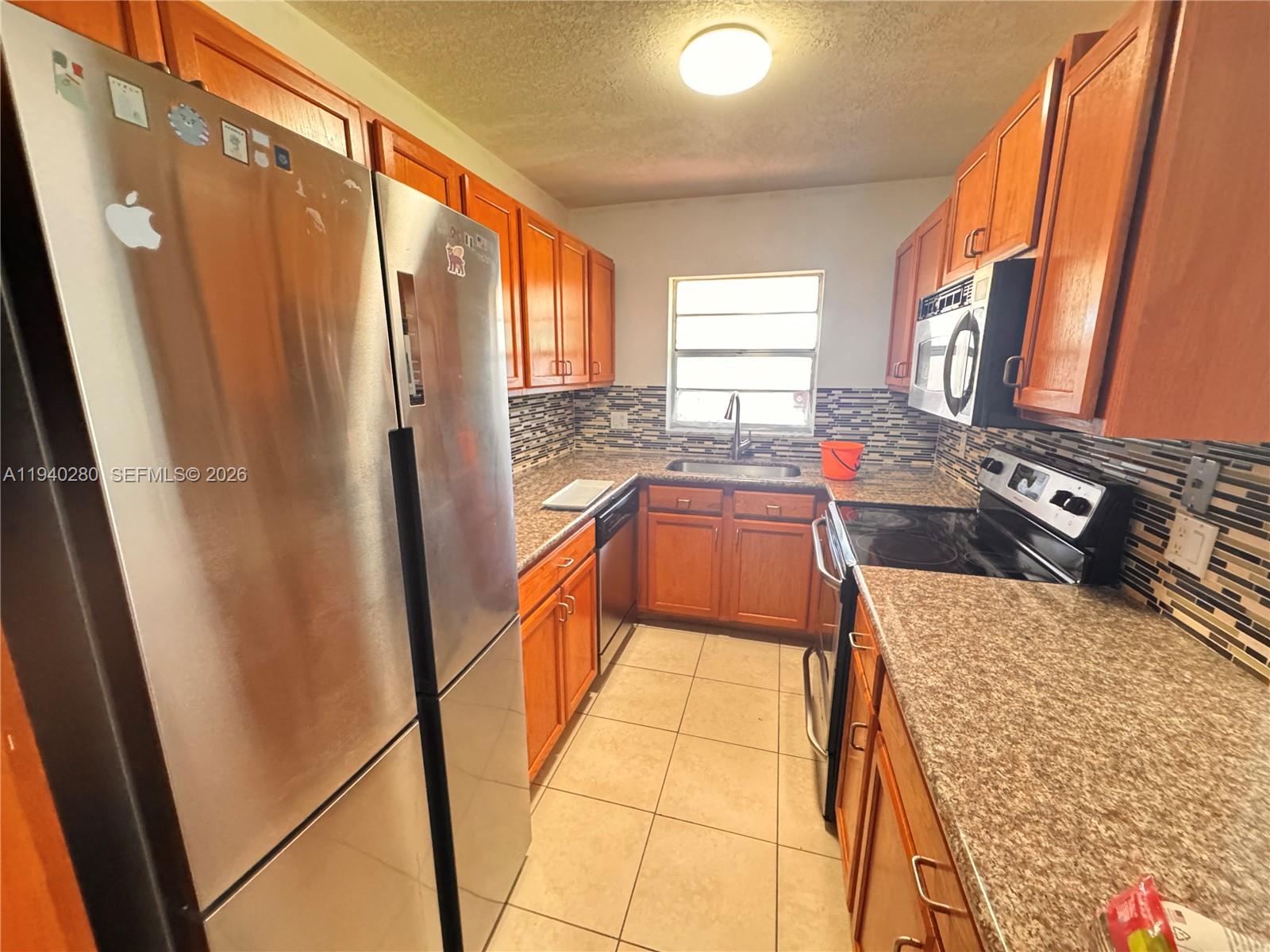 a kitchen with stainless steel appliances granite countertop a refrigerator a stove and a sink