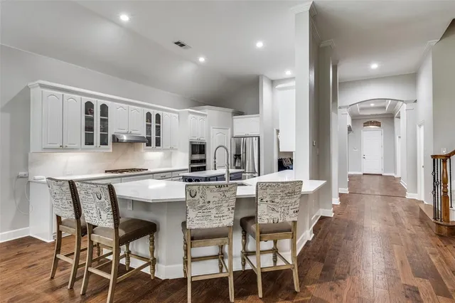 a kitchen with stainless steel appliances kitchen island granite countertop a table chairs sink and cabinets