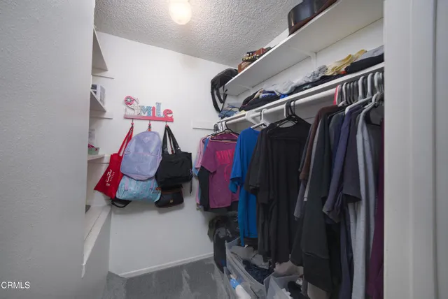 a view of walk in closet with clothes and shoes