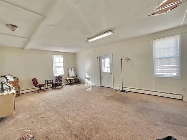 an empty room with windows and view of living room