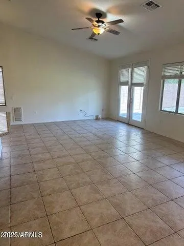 an empty room with windows and ceiling fan