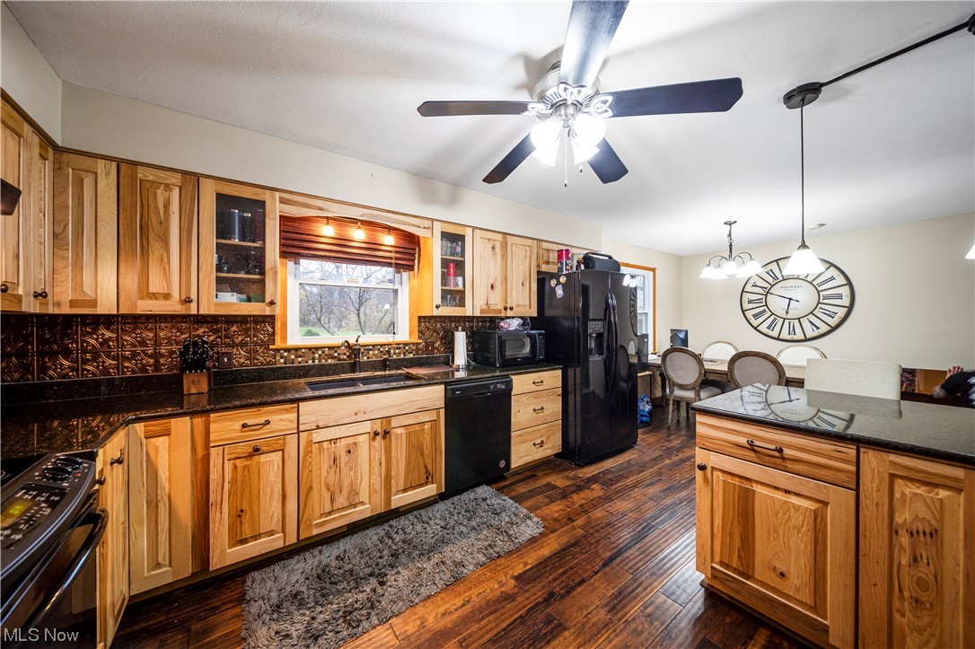 9944 Hoose Road Mentor, OH 44060 - Photo 3 of 35 Kitchen with ceiling fan with notable chandelier, hanging light fixtures, dark wood-type flooring, black appliances, and backsplash
