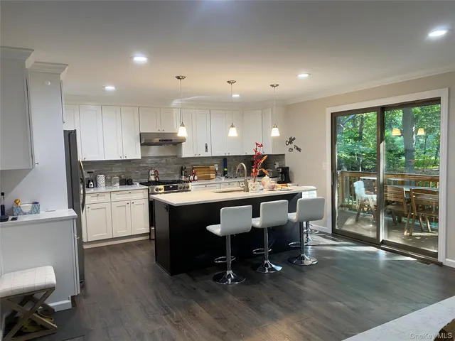 a kitchen with kitchen island granite countertop wooden floors and white stainless steel appliances