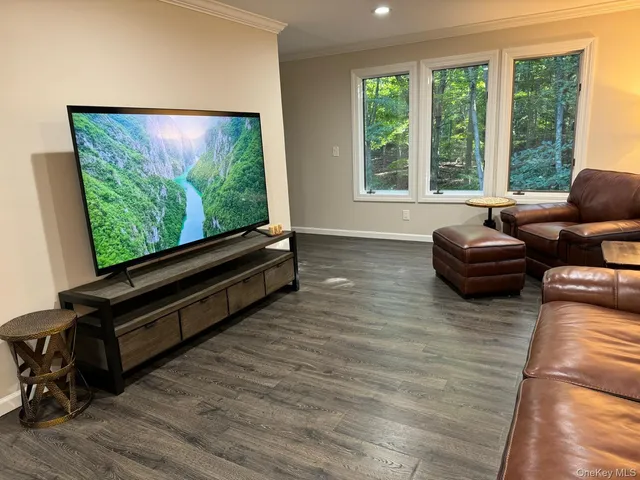 a living room with furniture flat screen tv and a large window