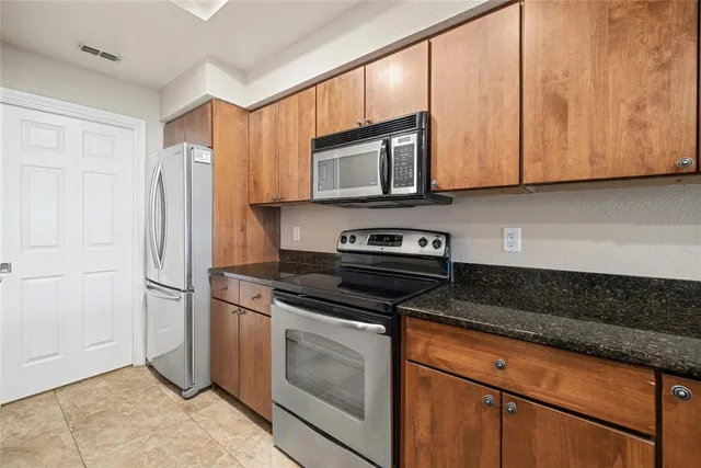 a kitchen with stainless steel appliances granite countertop a stove microwave and refrigerator