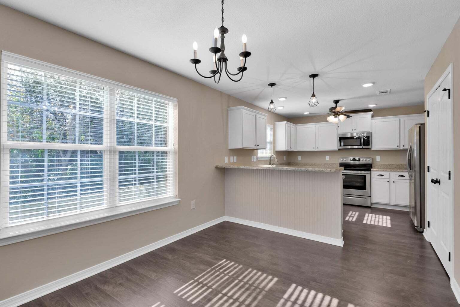446 Eisenhower Drive Crestview, FL 32539 - Photo 4 of 25 a kitchen with stainless steel appliances granite countertop a refrigerator a sink dishwasher a stove and a dining table with wooden floor
