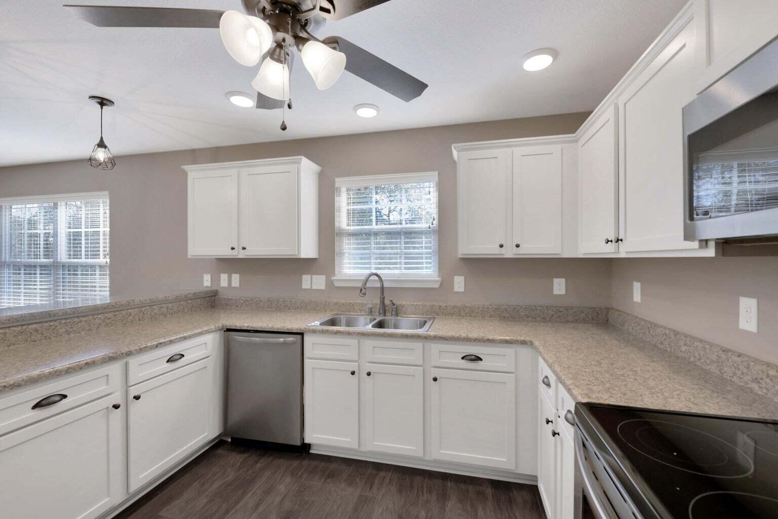 446 Eisenhower Drive Crestview, FL 32539 - Photo 8 of 25 a kitchen with a sink dishwasher and white cabinets with wooden floor