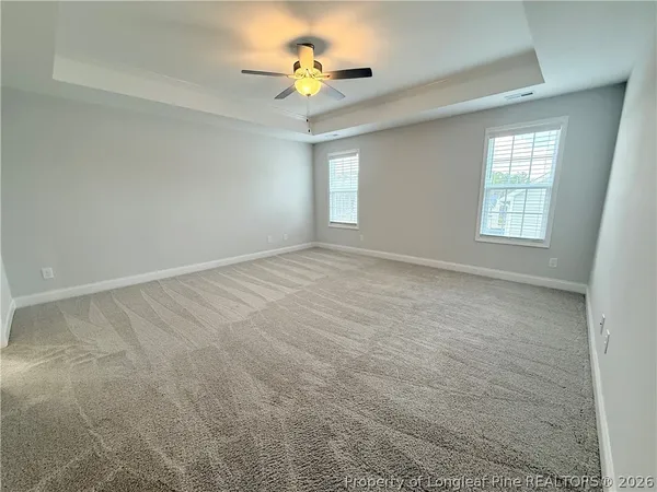 an empty room with windows and chandelier fan